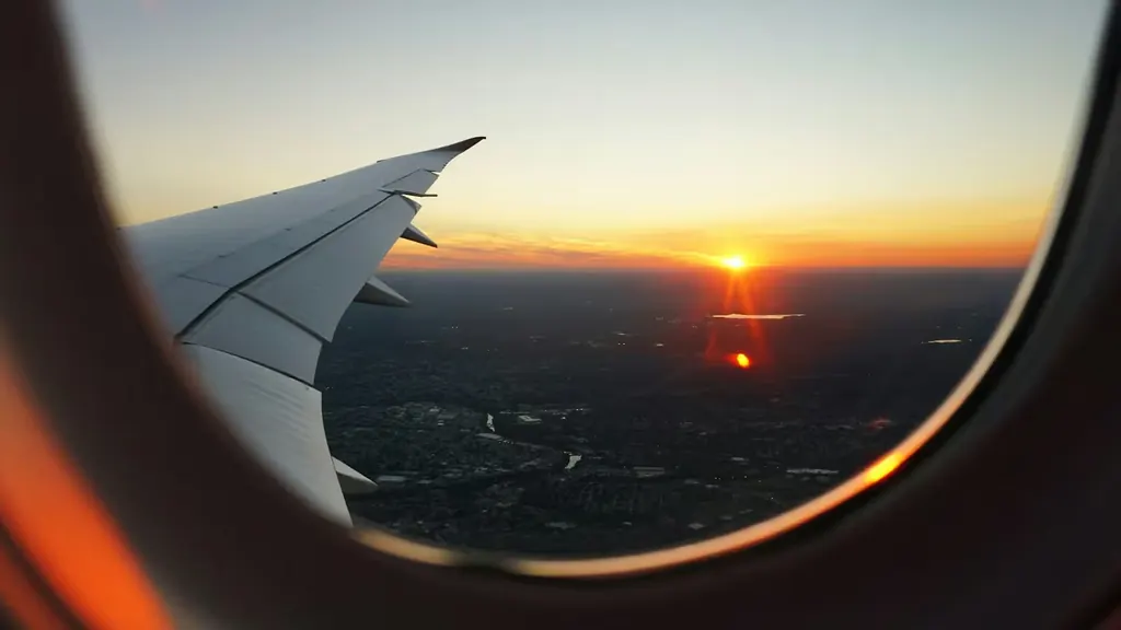 Plane wing seen through a cabin window at sunset